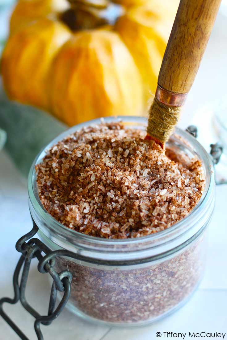 A jar of these Pumpkin Spice Bath Salts sits with a spoon in it, ready to use in your next, relaxing bath.