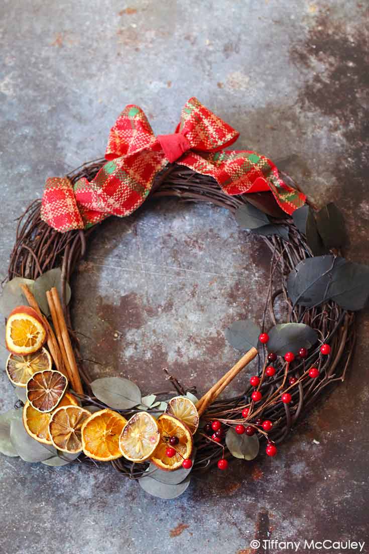 A beautiful citrus wreath with citrus slices, bay leaves and red berries to hang on your door or in your house.