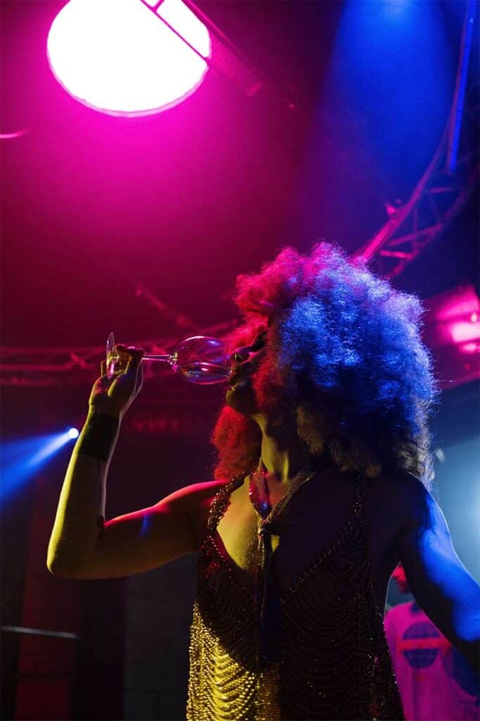 A woman drinking a glass of wine in a night club.