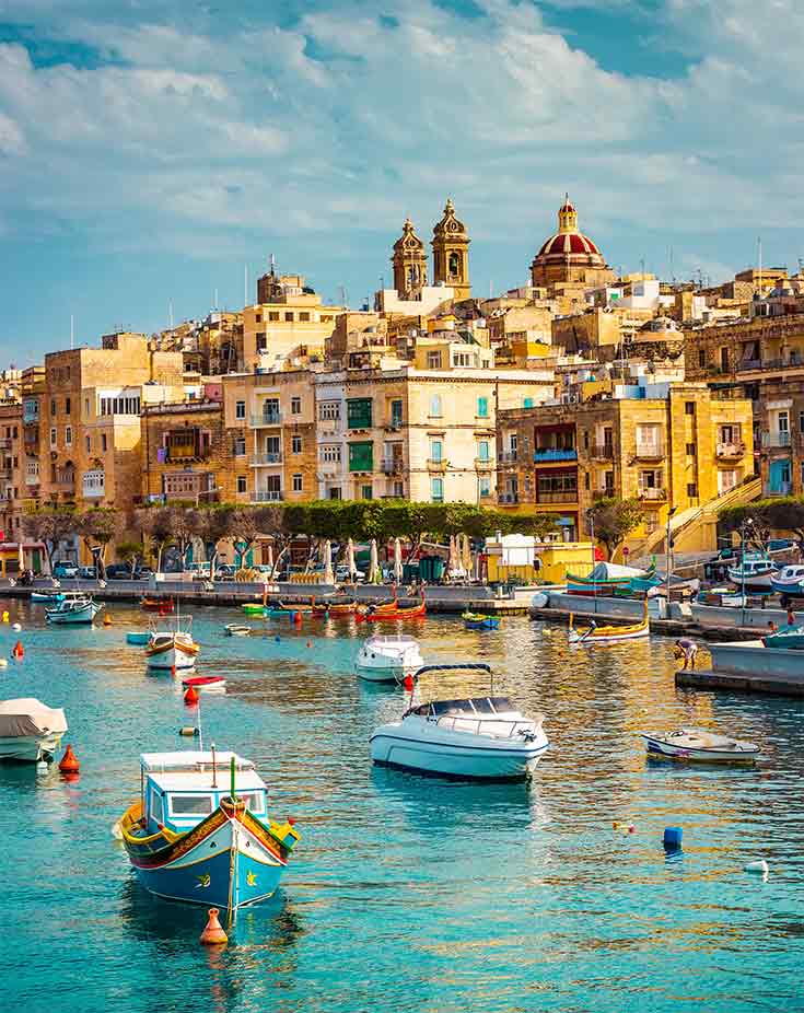 A view of boats in a canal along a Malta city harbor.