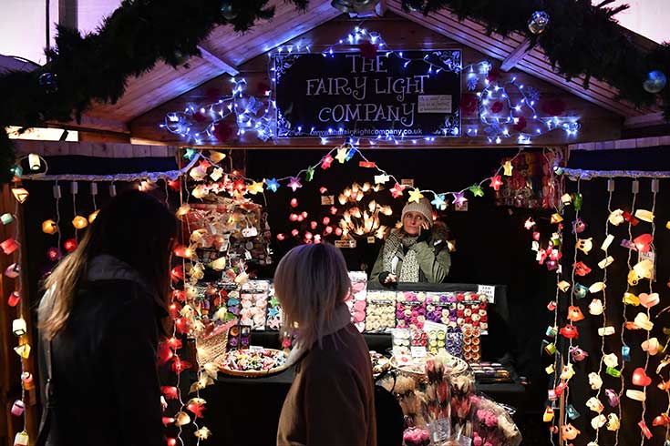 Image of a Christmas fair booth filled with fairy lights in Bath, England.