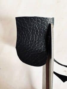 Cutting black eyes from faux leather fabric.