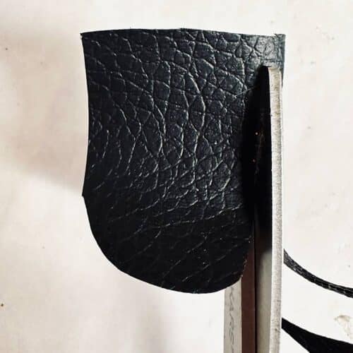 Cutting black eyes from faux leather fabric.